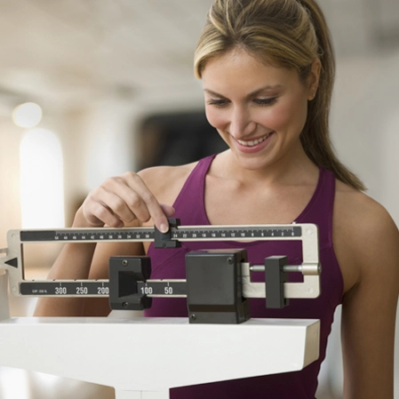 Woman weighing herself on scale, smiling